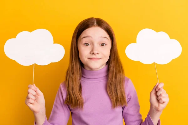 Photo of young beautiful smiling positive pretty little girl hold paper clouds on sticks isolated on yellow color background — Stock Photo, Image