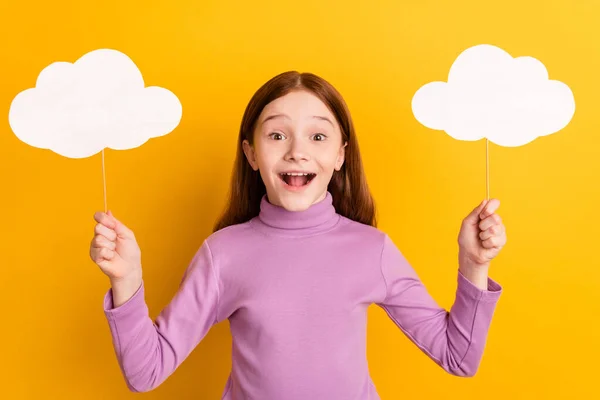 Φωτογραφία του χαρούμενος ενθουσιασμένος τρελό έκπληκτος μικρό κορίτσι κατέχουν δύο σύννεφα χαρτί που απομονώνονται σε κίτρινο φόντο χρώμα — Φωτογραφία Αρχείου