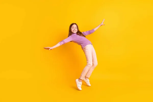 밝은 미소를 짓고 있는 행복 한 소녀가 노란 배경에서 혼자 서 춤을 추고 있는 모습의 전체 사이즈 사진 — 스톡 사진