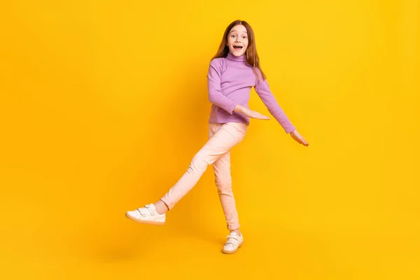 즐거운 기분으로 가득 한 행복 한 어린 소녀가 노란 배경에서 자유 시간을 즐기며 춤을 추는 사진 전체 — 스톡 사진