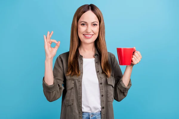 Fénykép a boldog pozitív érett nő hold csésze tea, hogy rendben énekelni ujjak elszigetelt kék színű háttér — Stock Fotó