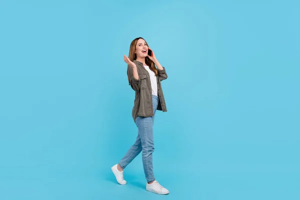 Full size photo of cheerful positive mature woman walk weekend talk phone conversation on blue color background — Stock Photo, Image