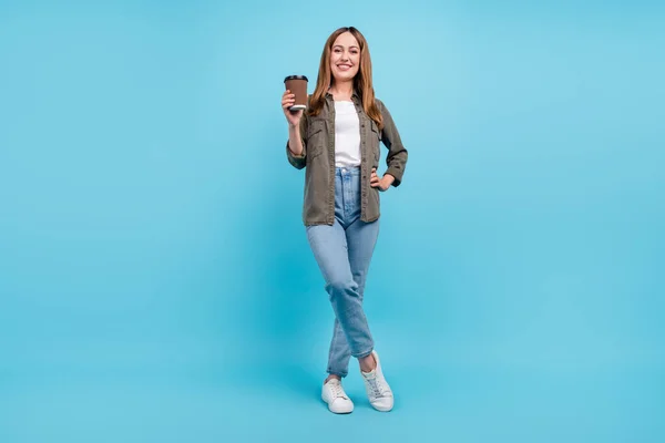 밝고 긍정적 인 성숙 한 여성의 전신 사진은 파란 배경에 분리 된 커피 테이크 웨이를 들고 있다 — 스톡 사진