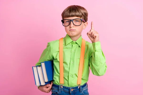 Foto de niño pequeño preadolescente dedo dedo idea inteligente educación escolar libro aislado sobre fondo de color rosa —  Fotos de Stock
