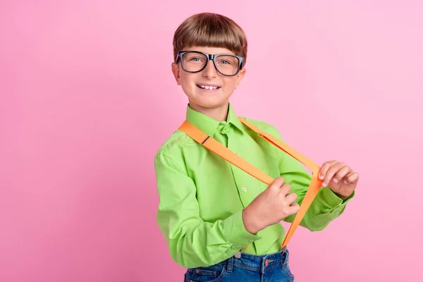 Profil boczne zdjęcie młodego chłopca szkoły zabawy ciągnąć szelki nosić okulary izolowane na różowym tle koloru — Zdjęcie stockowe