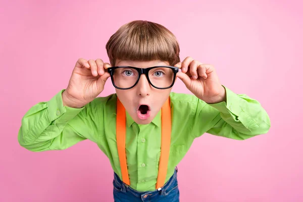 Foto av ung liten pojke händer röra glasögon förvånad chockad syn isolerad över rosa färg bakgrund — Stockfoto