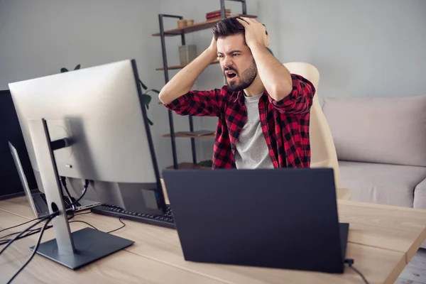 Foto van ongelukkige overstuur jongeman kijken scherm pc fout code software zitten bureau handen hoofd binnen kantoor — Stockfoto