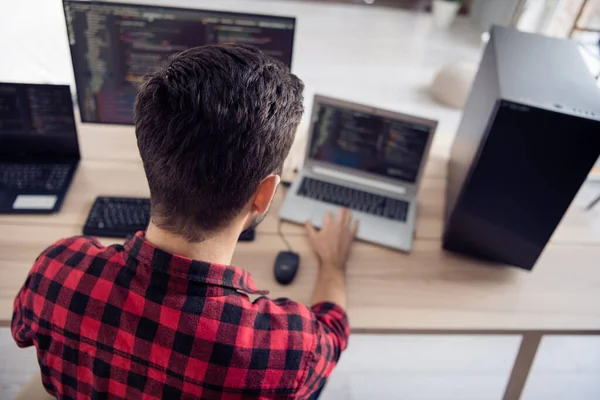 Achterzijde ruggengraat foto van jonge man zitten bureau werk code te ontwikkelen software te schrijven binnen kantoor werkplek — Stockfoto