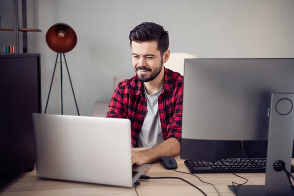 Foto van vrolijke jongeman look schrijf laptop zit bureau programmeur laptop binnen op kantoor — Stockfoto