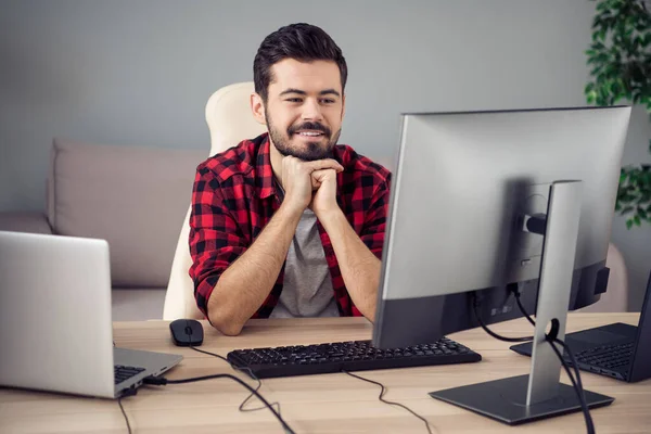 Φωτογραφία του ελκυστικού θετικού νεαρού άνδρα εμφάνιση οθόνη pc προγραμματιστής κάθονται τραπέζι εργασίας στο γραφείο σε εσωτερικούς χώρους στο χώρο εργασίας — Φωτογραφία Αρχείου