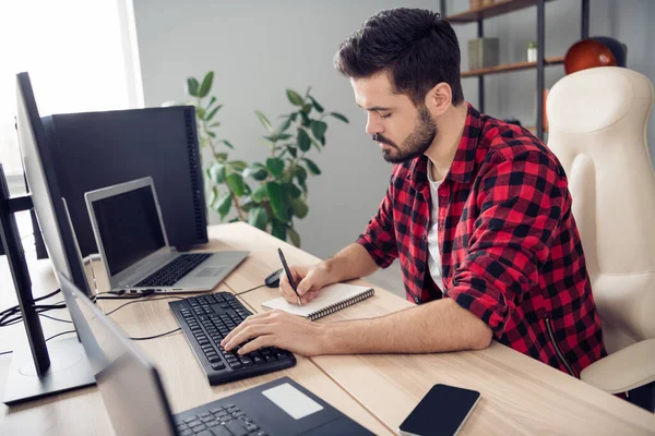 Perfil da foto lateral do jovem homem focado escrever notebook programador de computador dentro de casa no local de trabalho do escritório — Fotografia de Stock