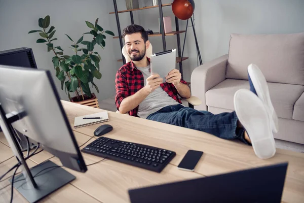 Полноразмерная фотография счастливого молодого жизнерадостного человека, сидящего за столом с планшетным компьютером внутри офиса — стоковое фото