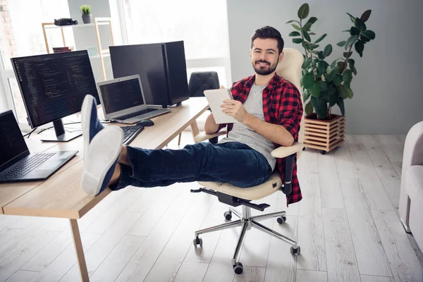 Фотографія повного тіла щасливого молодого веселого чоловіка, який пише блокнот хороший кодувальник настрою ПК сидить на столі всередині офісу — стокове фото