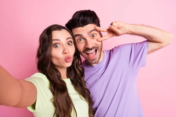 Autorretrato de amigos hermosos amistad pareja alegre de moda abrazando mostrando v-signo de los labios del puchero aislado sobre el fondo de color pastel rosa —  Fotos de Stock