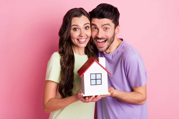 Retrato de la encantadora pareja alegre asombrada abrazando la celebración de crédito en casa banco aislado sobre fondo de color pastel rosa —  Fotos de Stock