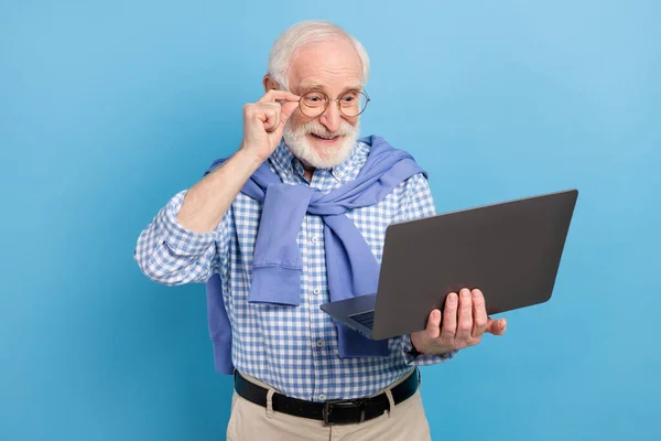 Zdjęcie optymistyczne stary szary włosów człowiek trzymać laptopa nosić okulary niebieska koszula izolowane na pastelowym tle koloru — Zdjęcie stockowe