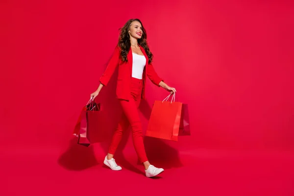 フルサイズの写真のファンキーな可愛いですブルネット女性行きますショッピングウェアスーツ靴孤立した上赤い色背景 — ストック写真