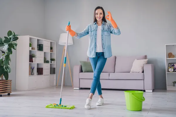 Foto em tamanho completo de morena millennial legal senhora lavar chão mostrar okey usar jeans camisa sapatilhas luvas em casa sozinho — Fotografia de Stock