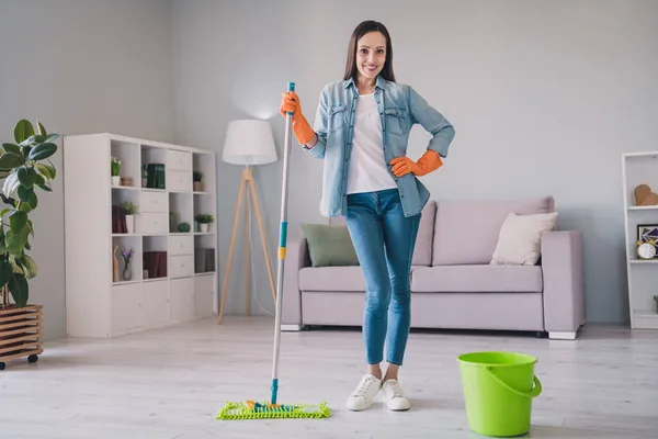 In voller Länge Foto der brünetten jungen Dame waschen Boden tragen Jeans Hemd Schuhe Handschuhe allein zu Hause — Stockfoto