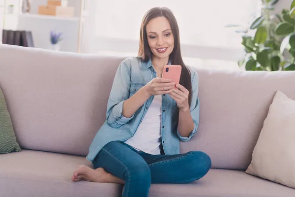 Ritratto di attraente donna dai capelli lunghi e allegra seduta sul divano con gadget post smm media a casa leggera all'interno — Foto Stock