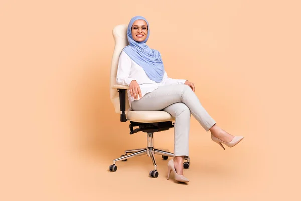 Corpo inteiro foto de milenar leste moderno senhora sentar usar lenço de cabeça camisa calças de óculos estilete isolado no fundo bege — Fotografia de Stock