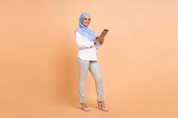 Volledige lichaam foto van millennial oosten moderne dame schrijven tablet dragen hoofddoek shirt brillen broek stiletto 's geïsoleerd op beige achtergrond — Stockfoto