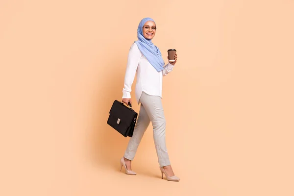 フルボディ写真の若いアラビア現代女性行きますとともにコーヒーバッグ着用スカーフシャツアイウェアパンツstilettos隔離された桃の背景 — ストック写真