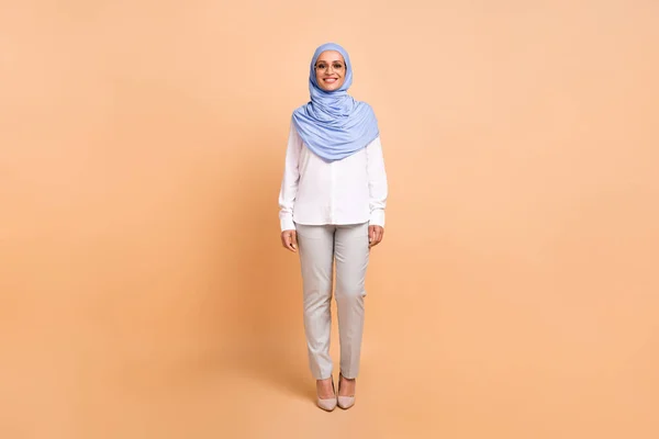 フルサイズの写真の若いアラビア語のマネージャー現代の女性スタンドは、桃の色の背景に隔離された高ヒールの頭のスカーフシャツのアイウェアパンツ — ストック写真