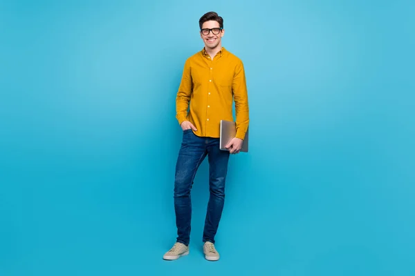 Neşeli serbest programcı adamın fotoğrafı PC tutun sarı gömlek pantolon giyin izole edilmiş mavi arka plan ayakkabıları — Stok fotoğraf
