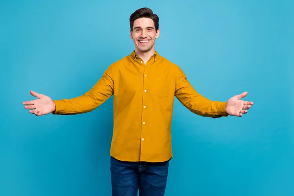 Foto de cara hospitaleiro amigável convidar abraçar desgaste camisa amarela jeans isolado azul cor fundo — Fotografia de Stock
