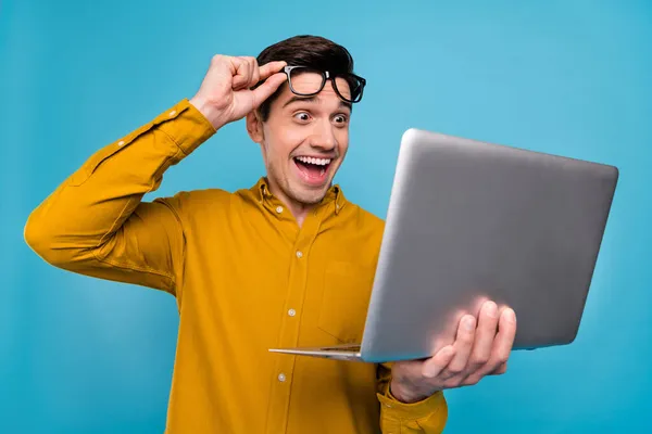 Photo de hooray brunet manager homme look ordinateur portable porter chemise jaune lunettes isolées sur fond de couleur bleue — Photo