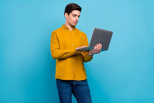 Foto van ernstige programmeur kerel houden laptop stuur e-mail slijtage geel shirt geïsoleerde blauwe kleur achtergrond — Stockfoto