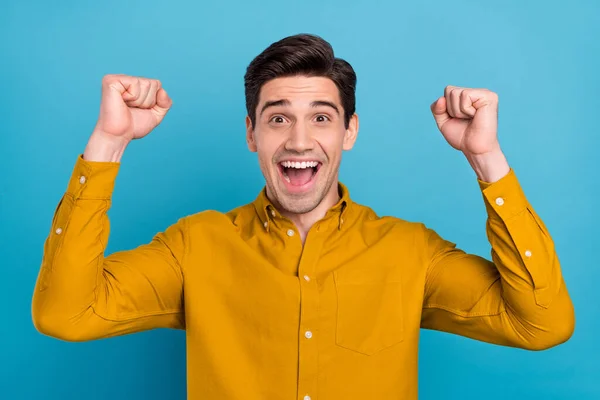 Foto de chico asombrado levantar los puños boca abierta gritar objetivo usar camisa amarilla aislado color azul fondo — Foto de Stock