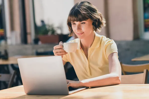 Foto di lavoro millenaria bruna signora bere tè tipo laptop indossare t-shirt gialla al di fuori nel parco — Foto Stock