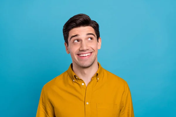 Zdjęcie pod wrażeniem marzycielski młody człowiek nosić żółtą koszulę patrząc puste miejsce uśmiechając się odizolowany niebieski kolor tła — Zdjęcie stockowe