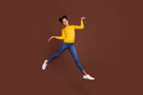 Foto de tamaño completo de niña preadolescente activa salto usar camisa jeans zapatos aislados en el fondo de color marrón —  Fotos de Stock