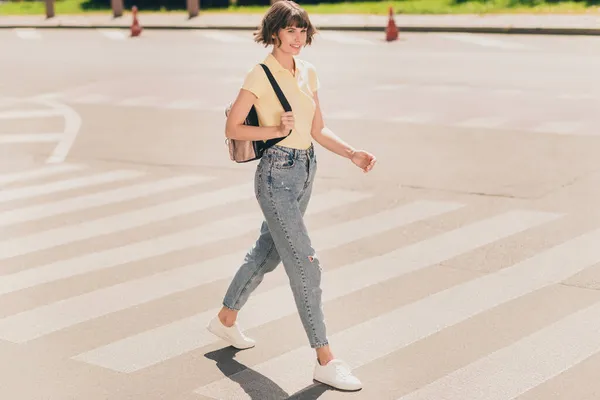 Full storlek foto av trevlig ung brunett dam gå bära t-shirt jeans sneakers utanför i parken — Stockfoto