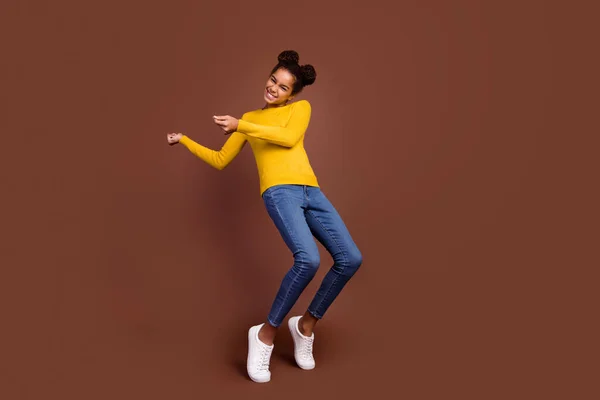 Foto em tamanho completo de menina dança desgaste pulôver calça jeans isolado no fundo de cor marrom — Fotografia de Stock