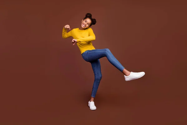 Foto de tamaño completo de niña pequeña hacer deporte desgaste suéter jeans zapatos aislados sobre fondo de color marrón —  Fotos de Stock