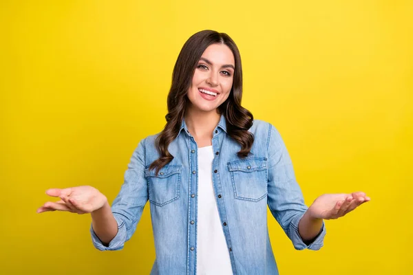 Foto de dulce encantadora joven dama usar jeans camisa sonriente mostrando brazos escamas espacio vacío aislado color amarillo fondo — Foto de Stock