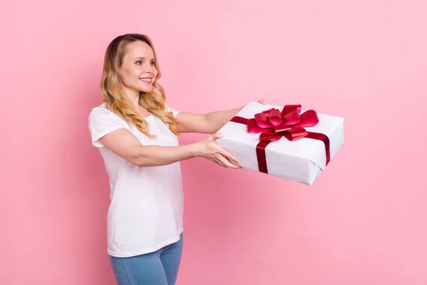 Photo de positive jolie jeune femme tenir la main boîte cadeau donner un espace vide isolé sur fond de couleur rose — Photo