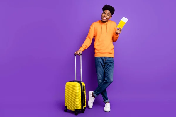 Полное фото тела очаровательной брюнетки афро-американский молодой человек держать билеты носить джинсы багажа изолированы на фиолетовом фоне цвета — стоковое фото