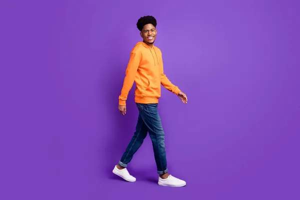 Foto de cuerpo completo del hombre afro americano feliz positivo caminar vacío espacio sonrisa aislada sobre fondo de color púrpura —  Fotos de Stock
