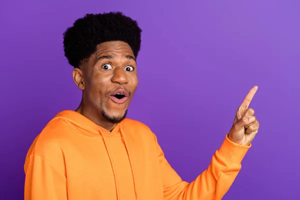 Foto van aantrekkelijke jonge Afro-Amerikaanse man wijzen vinger lege ruimte schok verkoop geïsoleerd op paarse kleur achtergrond — Stockfoto