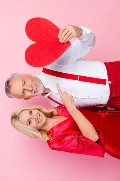 Retrato de dos hermosos compañeros de vida alegres de moda guapos demostrando tarjeta de forma de corazón aislado sobre fondo de color pastel rosa — Foto de Stock