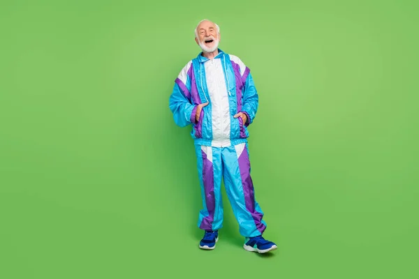 Çekici yaşlı adamın spor takım elbise giyip gülüşü yeşil renkli arka plan. — Stok fotoğraf