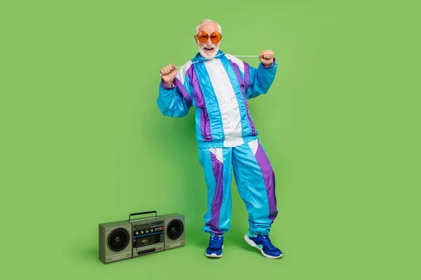 Φωτογραφία του γοητευτικό αστείο ώριμος τύπος ντυμένος μπλε σπορ κοστούμι σκούρα γυαλιά χαμογελώντας ακούγοντας μπουμ κουτί απομονωμένο πράσινο χρώμα φόντο — Φωτογραφία Αρχείου