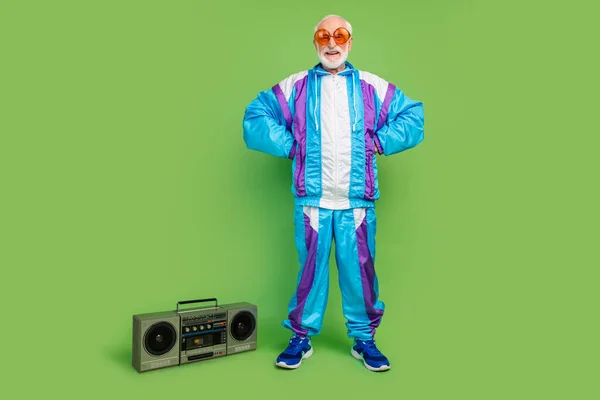 Foto van funky grappige senior man dragen sportief pak donkere oogkledij luisteren boombox glimlachen geïsoleerde groene kleur achtergrond — Stockfoto
