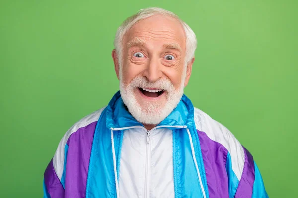 Фотографія привабливого враженого старшого чоловіка в спортивному костюмі, усміхнений великими очима, ізольований зелений кольоровий фон — стокове фото