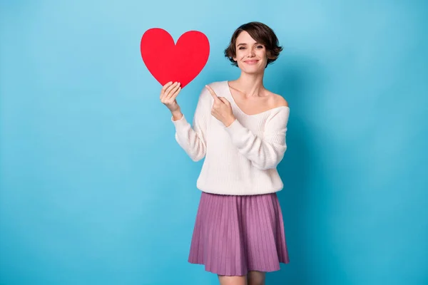 Foto de jovem atraente bonito feliz positivo sorridente menina apontar dedo no coração vermelho grande isolado no fundo de cor azul — Fotografia de Stock